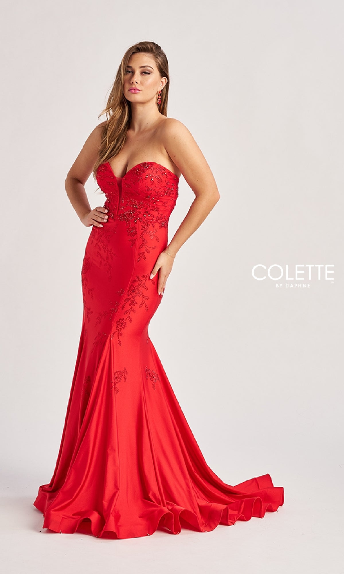 A woman stands against a plain light background wearing the Colette by Daphne Long Prom Dress CL8445—a strapless, floor-length red gown featuring a sweetheart neckline and embroidered details.